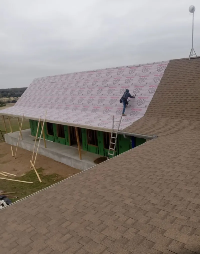 Worker preparing underlayment for a metal roof installation in Collegeville